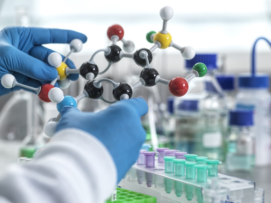 Scientist holding a molecular model in a laboratory setting.